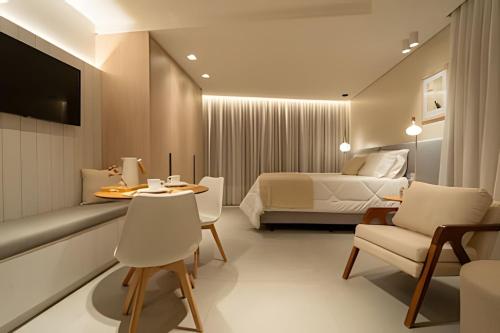 ein Hotelzimmer mit Bett, Tisch und Stühlen in der Unterkunft Lofts amplos e sofisticados a 600m da Vila Germânica in Blumenau