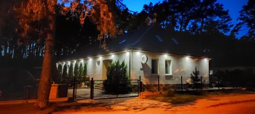 a white house with lights on it at night at Sosnówka Pokoje Gościnne in Borne Sulinowo