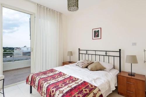 ein Schlafzimmer mit einem Bett und einem großen Fenster in der Unterkunft Mountain & Seaview Penthouse in a Holiday Village2 in Ayios Yeoryios