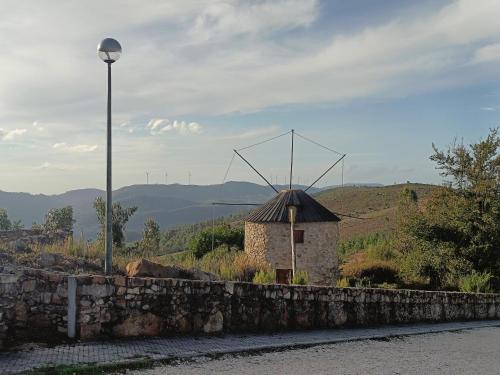 a windmill on a hill next to a stone wall at Moinhos do Alecrim in Penacova
