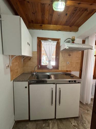 a kitchen with white cabinets and a sink and a window at Marias Apartments in Vasiliká