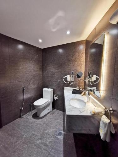 a bathroom with a toilet and a sink and a mirror at فندق امان - أحد رفيدة in Ahad Rafidah