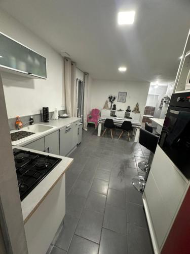 Il comprend un salon et une cuisine équipée d'appareils électroménagers blancs. dans l'établissement Domaine des roses - Charmante Maison à Louer, à Sonzay