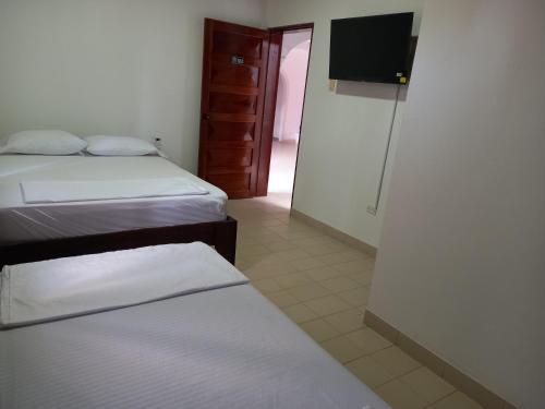 a bedroom with two beds and a flat screen tv at El Jaguar Casa Hotel in Leticia