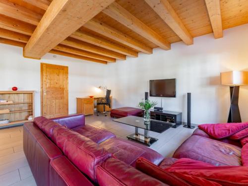 a living room with a red couch and a tv at Maxima - Ski in - Ski Out in Flecken