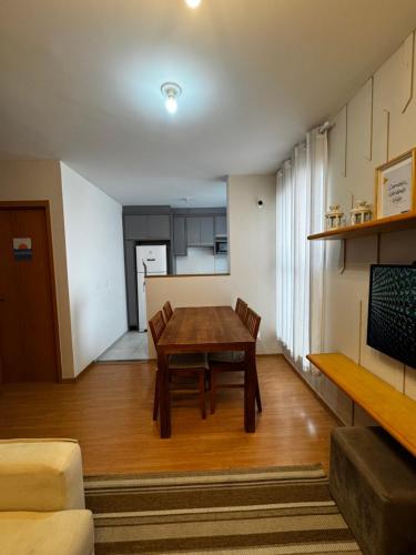 a living room with a wooden table and a kitchen at Apartamento próximo às principais praias de Florianópolis in São José