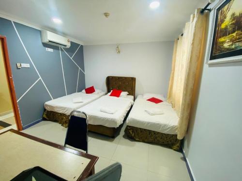 two beds in a room with a table and chairs at Kk INN HOTEL in Kuala Ampang