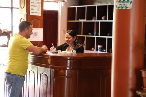 Ein Mann und eine Frau stehen an einer Bar in der Unterkunft QASANA HOTEL Plaza Calca in Calca