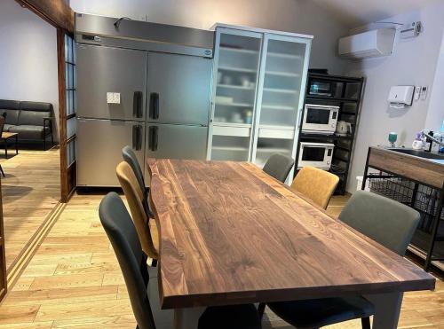 a dining room with a wooden table and chairs at Guesthouse TOMARITOMARO in Shikineshima