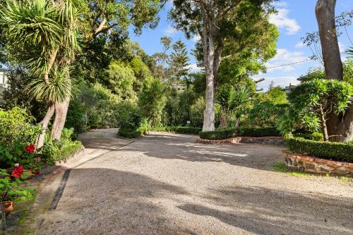 a gravel driveway with palm trees and bushes at The Castle - Villa by the Sea in Cowes
