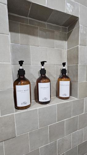 three bottles of soap on a shelf in a bathroom at Inn History Tombstone in Tombstone
