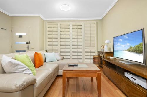 a living room with a white couch and a flat screen tv at Family 3BR 2-level Home at Central Chatswood in Sydney