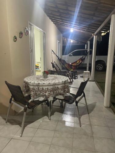 a patio with a table and chairs and a hammock at Chácara Lara Bela in Praia do Saco