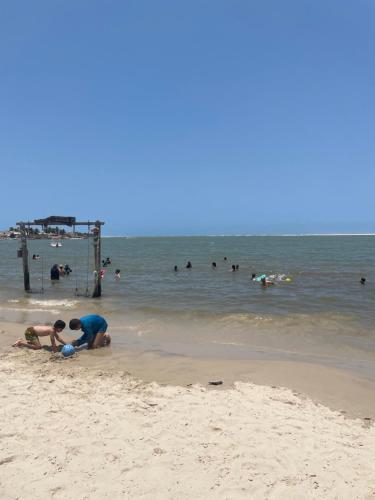 two people playing in the sand at the beach at Chácara Lara Bela in Praia do Saco