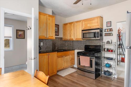 a kitchen with wooden cabinets and a black stove top oven at Snapdragon Apt - Charming Two Bedroom in Corcoran Neighborhood in Minneapolis