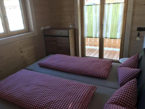 a room with purple cushions on a bench with windows at Resl Haus 1 Comfortable holiday residence in Jungholz