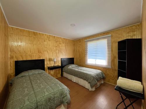 una camera da letto con due letti e una finestra di Cabaña en Malalcahuello a Malalcahuello