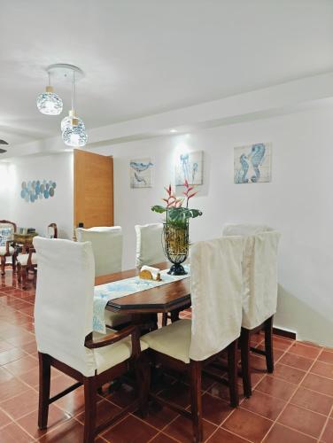 a dining room with a wooden table and white chairs at Sosua Sweet Vacations in Sosúa