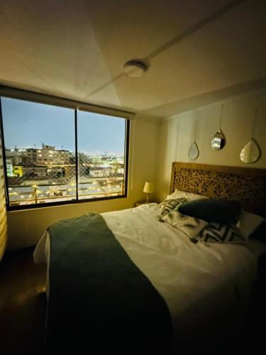 a bedroom with a large bed and a large window at Departamentos Real in Santiago