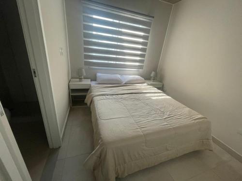 a bedroom with a bed and a window with blinds at Dpto Edificio Marlin Luque in Luque