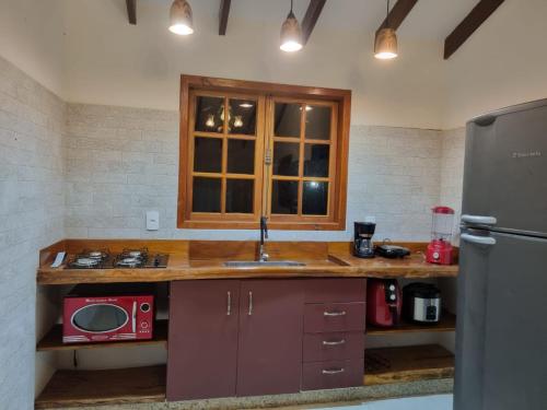a kitchen with a counter with a sink and a refrigerator at Sítio Quinta da mata - Casa Amarela in Pirenópolis