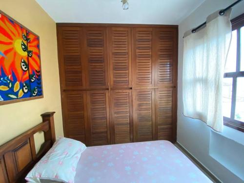 une chambre avec un lit et un tableau au mur dans l'établissement Apartamento Lelis - Descanso para a família e seu pet, pertinho do mar - praia Guarujá - SP, à Guarujá