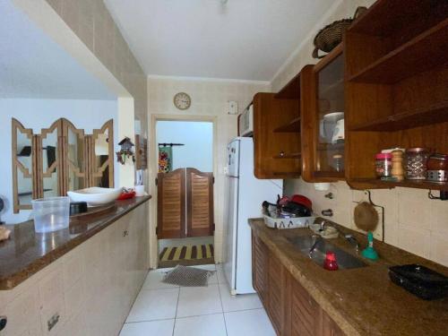 une cuisine avec un réfrigérateur et une porte menant à une chambre. dans l'établissement Apartamento Lelis - Descanso para a família e seu pet, pertinho do mar - praia Guarujá - SP, à Guarujá