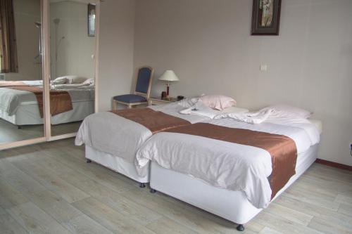 a bedroom with two beds and a mirror at Ambassador Suites Antwerp in Antwerp
