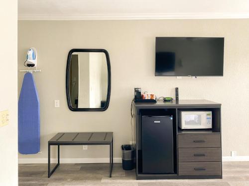 a room with a tv and a table and a mirror at Rockview Inn and Suites in Morro Bay