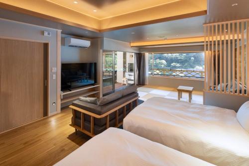 a bedroom with two beds and a flat screen tv at Hotel Okada in Hakone