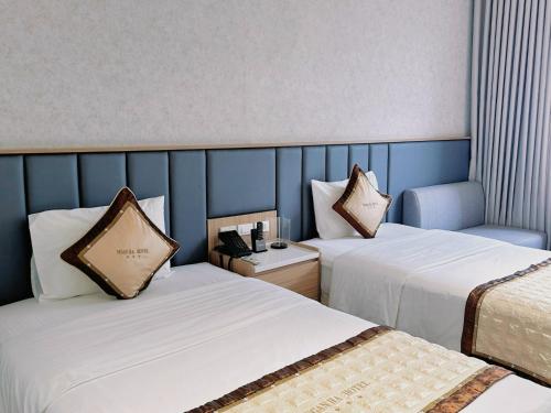 a hotel room with two beds and a blue wall at NGAN HA HOTEL in Ðại Tiêt