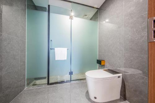 a bathroom with a toilet and a glass shower at 丽江古城丽漫酒店 in Lijiang