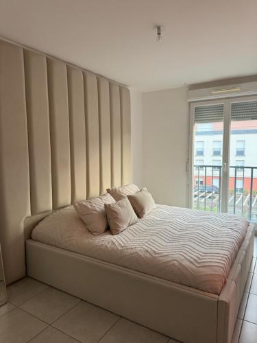 un lit dans une chambre avec une grande fenêtre dans l'établissement Superbe Appartement - Near Paris, à Corbeil-Essonnes
