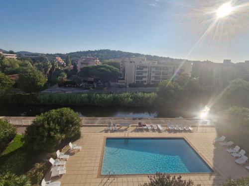 une piscine avec des chaises longues et un bâtiment dans l'établissement Beau 2 pièces climatisé avec terrasse et piscine, proche centre Sainte-Maxime - FR-1-780-85, à Sainte-Maxime
