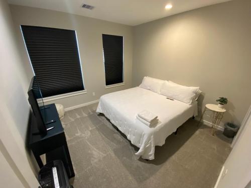 a bedroom with a white bed and two windows at Hidden Gem - Gated Community & Garage Parking in Houston