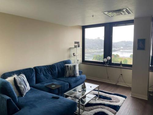 a living room with a blue couch and a large window at Luxury Apt at the Point Easy Access To and From Downtown 24-7 Parking in Pittsburgh