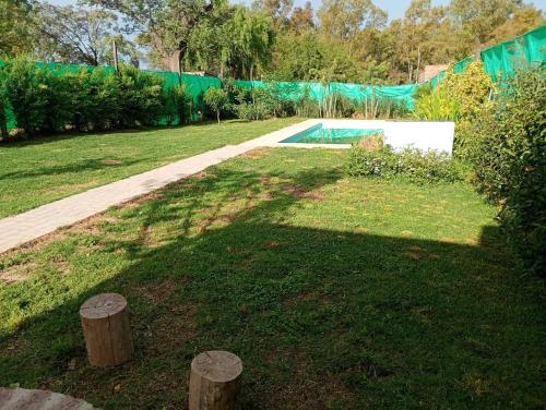 Un jardín con piscina y algunos árboles y una valla. en El nogalito quinta, en Lobos