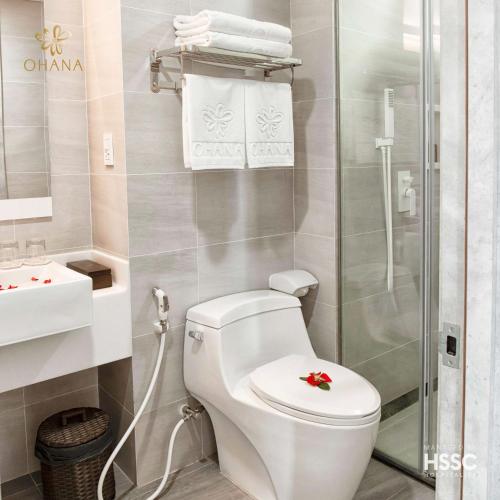 a white bathroom with a toilet and a shower at Ohana Village in Phương Phi