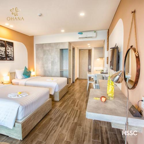 a hotel room with two beds and a desk at Ohana Village in Phương Phi