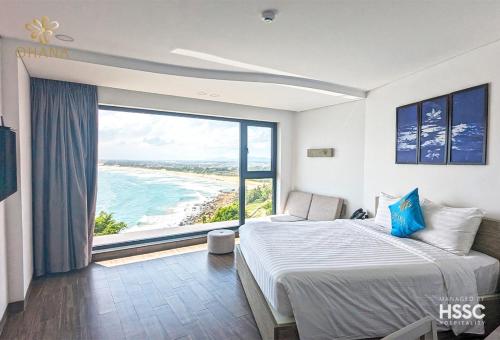 a bedroom with a bed and a large window with the ocean at Ohana Village in Phương Phi