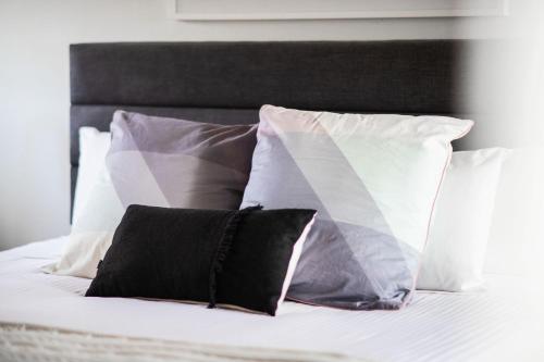 a bed with white pillows and black and white pillows at Silvertop Apartment in Crackenback