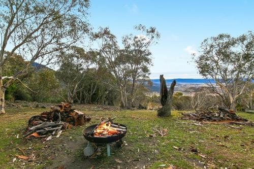 a barbecue grill with a fire in a field at Silvertop Apartment in Crackenback