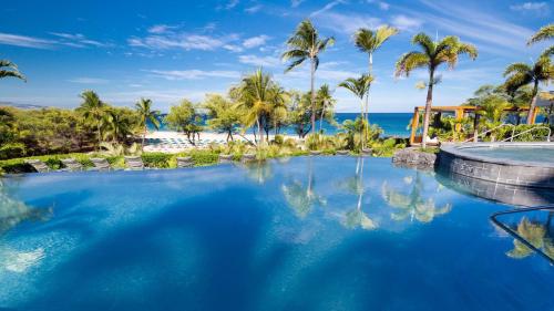 a swimming pool with palm trees and the ocean at ❤PiH❤ Beautiful Ocean Villa Nani Moana Hale Stunning Ocean Views in Hapuna Beach