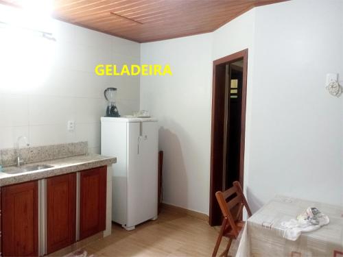 a kitchen with a white refrigerator and a sink at Pousada Lagoa Flat in Morro de São Paulo