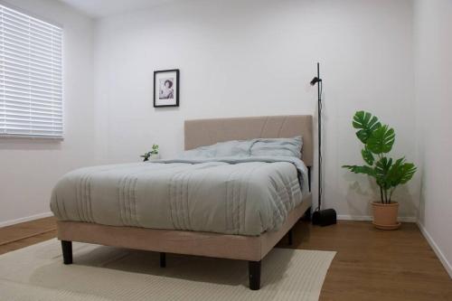 un letto in una camera da letto bianca con una pianta di Mountain View Oasis a Los Angeles