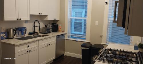 a kitchen with white cabinets and a sink and a stove at HomeStay in Boston - Dorchester Fields Corner Area in Boston