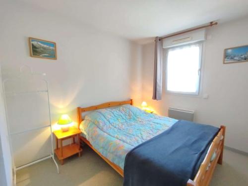 a bedroom with a bed with a blue bedspread and a window at Charmant T3 6 pers, terrasse sud, parking, centre St Lary Soulan - FR-1-457-357 in Saint-Lary-Soulan