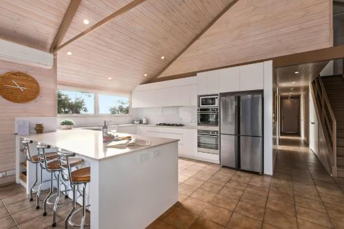 a kitchen with white appliances and a wooden ceiling at Silvertop Chalet in Crackenback