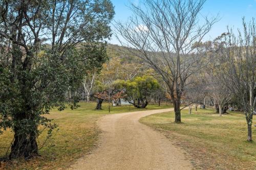 a dirt road in the middle of a field with trees at Silvertop Chalet in Crackenback