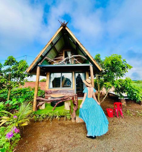 a woman in a blue dress standing in front of a house at Gia Huan Homestay - Tà Đùng in Biđong